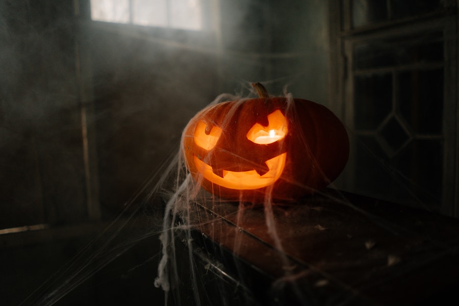 Spooky pumpkin covered in cobwebs in a hazy room