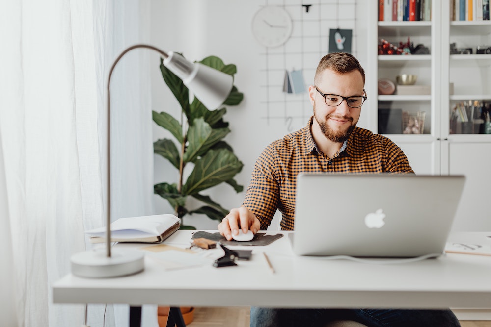 Smiling man sitting in front of Macbook