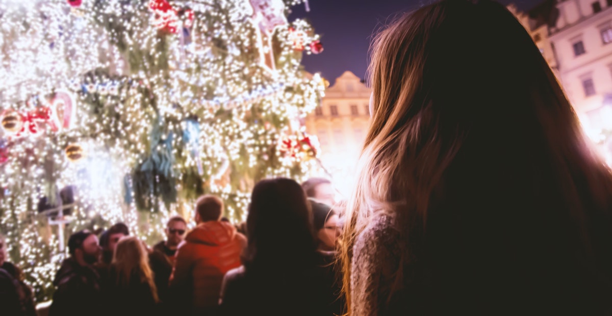 Crowd gathers around lit Christmas tree in public